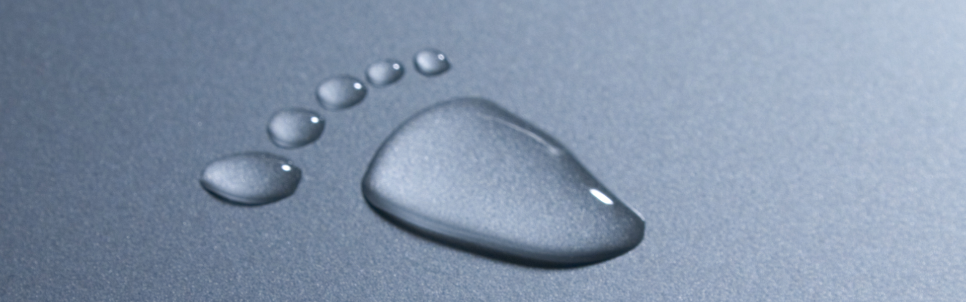 Wassertropfen bilden einen Fußabdruck auf grauen Hintergrund 